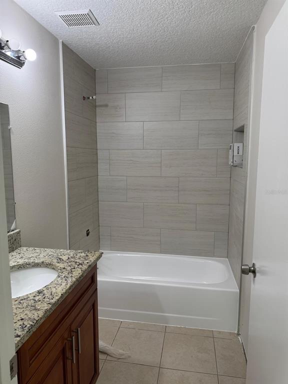A bathroom features a granite-topped vanity, a white bathtub, and light-colored horizontal wall tiles — 5272 LONESOME DOVE DRIVE, KISSIMMEE, FL