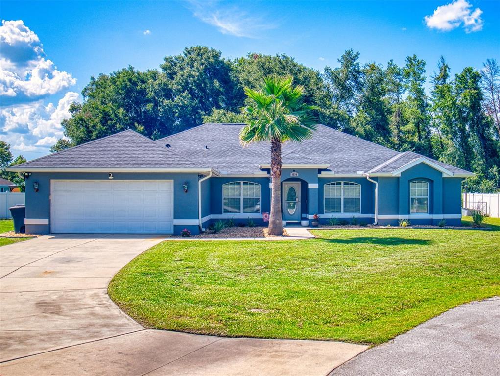 A blue single-story house with a two-car garage, a palm tree, and a grassy lawn — 9584 SW 42ND COURT, OCALA, FL