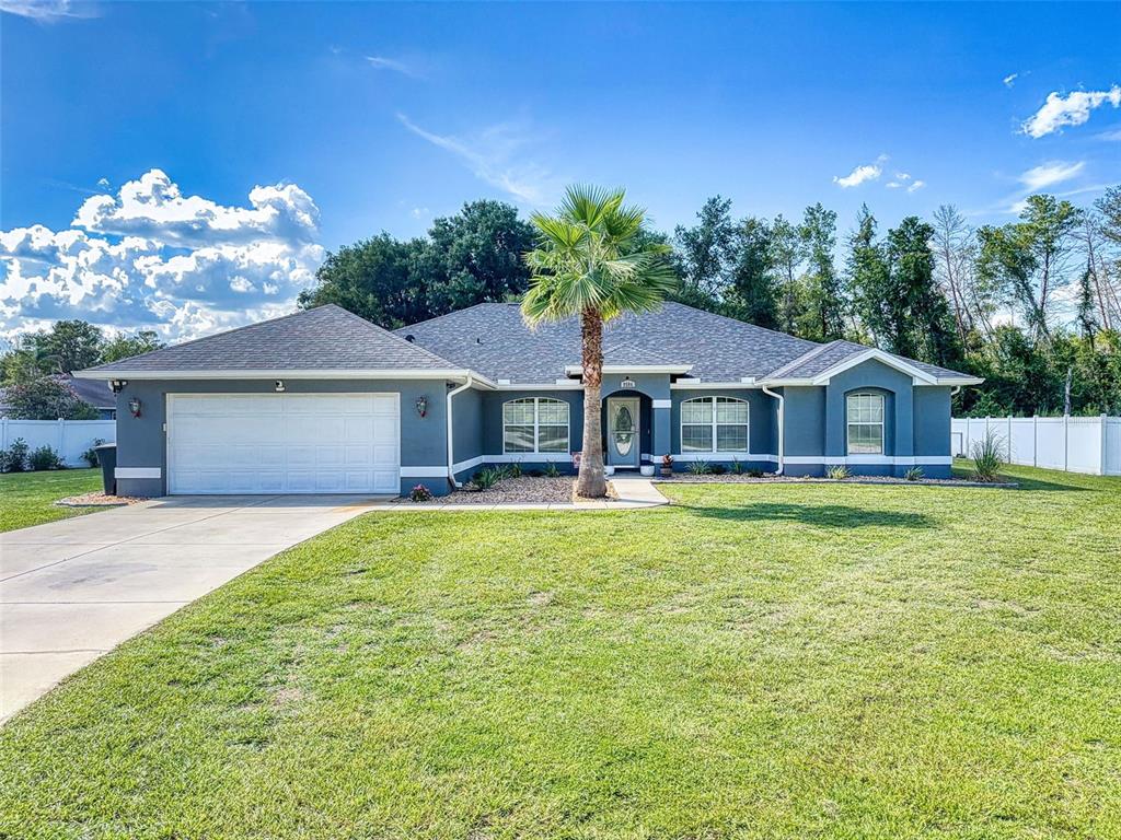 A single-story house with a gray exterior, a two-car garage, and a central palm tree — 9584 SW 42ND COURT, OCALA, FL
