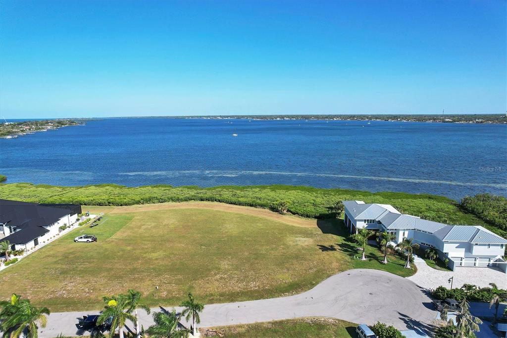An aerial view shows a vacant waterfront lot situated between two large residential homes — 5248 THE POINTE, ENGLEWOOD, FL