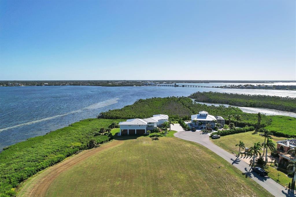 An aerial view shows two waterfront houses situated on a grassy lot near a bay — 5248 THE POINTE, ENGLEWOOD, FL