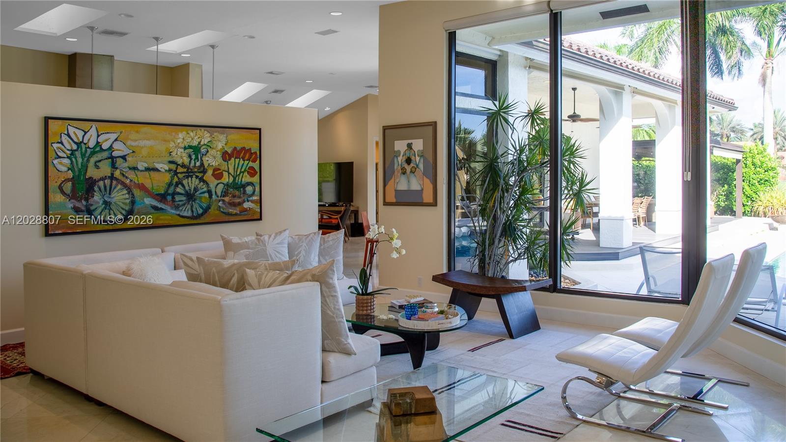 A bright living room features white sofas, modern chairs, large windows, and a colorful painting — 2880 Windmill Ranch Rd, Weston FL 33331, WESTON, FL