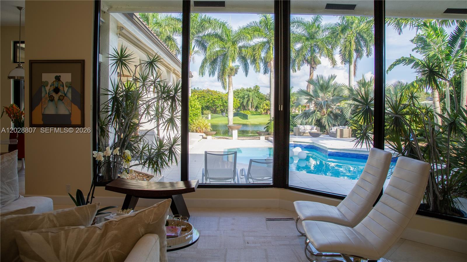 A living room with floor-to-ceiling windows overlooks a swimming pool and a lake — 2880 Windmill Ranch Rd, Weston FL 33331, WESTON, FL