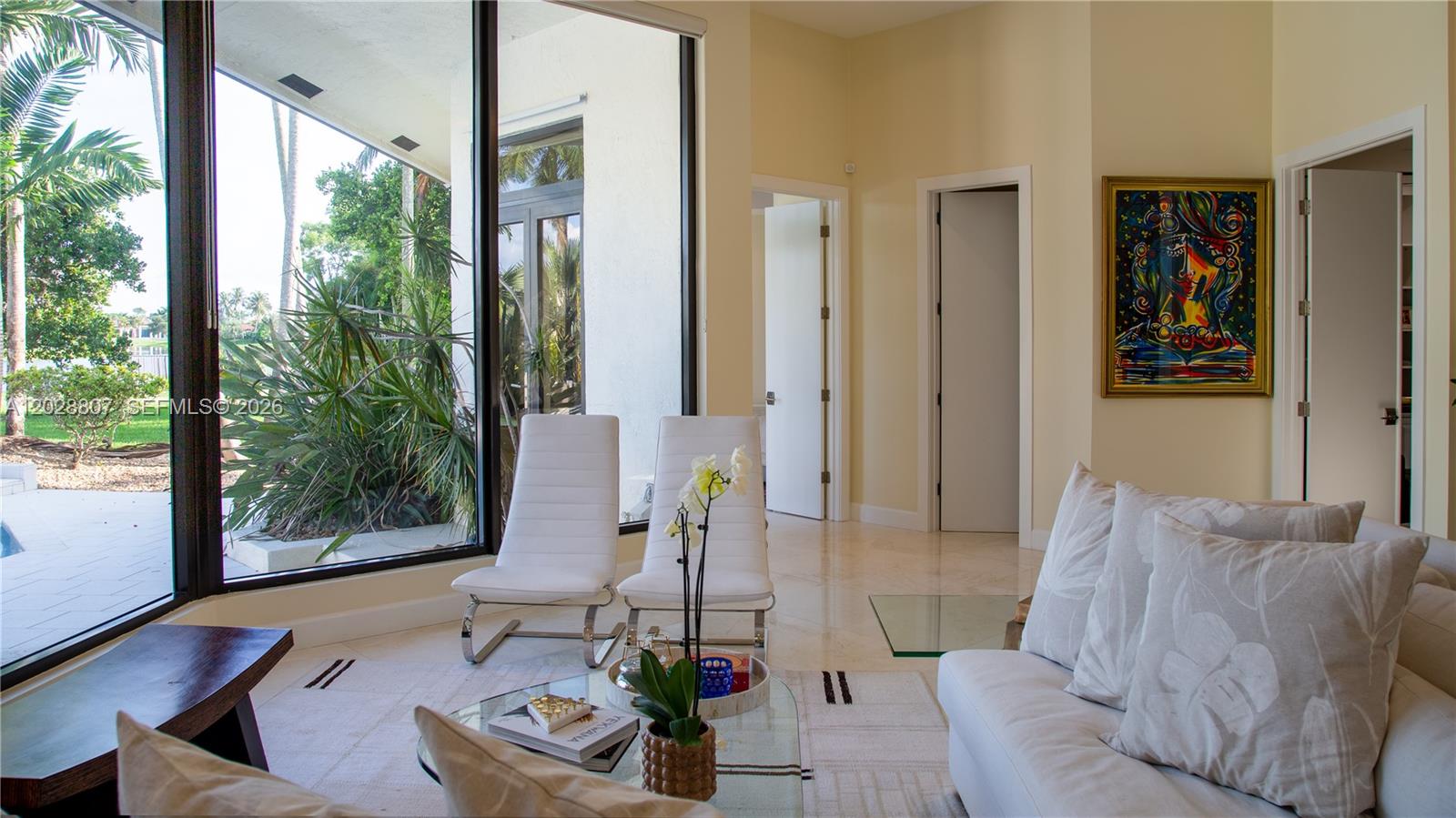 A living room features white chairs, a glass coffee table, and large windows overlooking greenery — 2880 Windmill Ranch Rd, Weston FL 33331, WESTON, FL
