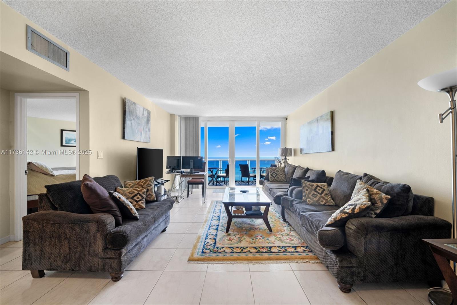 A living room features two dark sofas, a coffee table, and a balcony overlooking the ocean — 3725 S Ocean Dr # 1110, Hollywood FL 33019, HOLLYWOOD, FL