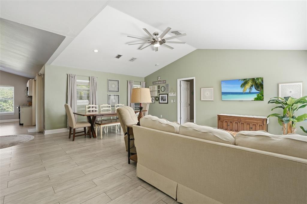 A living room and dining area with light green walls, vaulted ceilings, and tile flooring — 4934 SW 20TH PLACE, CAPE CORAL, FL