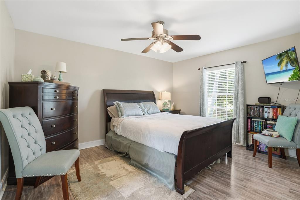 A bedroom features a dark wood bed frame, a matching dresser, and two light blue chairs — 4934 SW 20TH PLACE, CAPE CORAL, FL