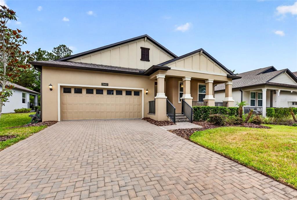 A single-story house with a tan stucco exterior, a paved driveway, and a covered porch — 19462 FOREST GARDEN COURT, BROOKSVILLE, FL