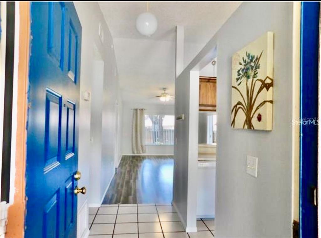 An entryway with a blue door, tiled floor, and a view into a living area — 107 SHADY OAK DRIVE, SANFORD, FL