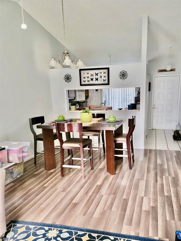 A dining area features a wooden table, four chairs, and a pass-through window to the kitchen — 107 SHADY OAK DRIVE, SANFORD, FL