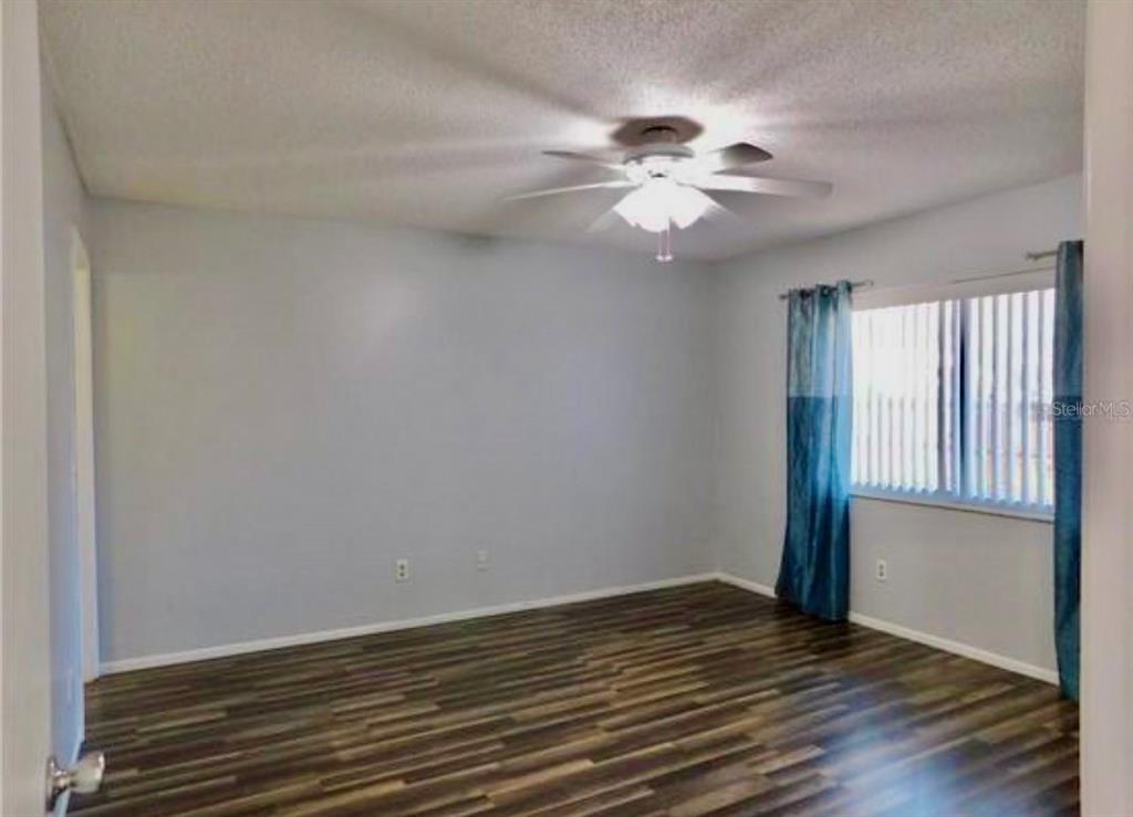 An empty bedroom features light blue walls, dark wood-look flooring, and a ceiling fan — 107 SHADY OAK DRIVE, SANFORD, FL