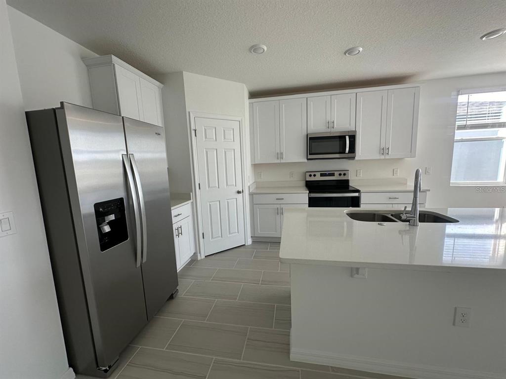 A modern kitchen features white cabinets, stainless steel appliances, and a central island — 2748 SAN MARCO WAY, WINTER HAVEN, FL