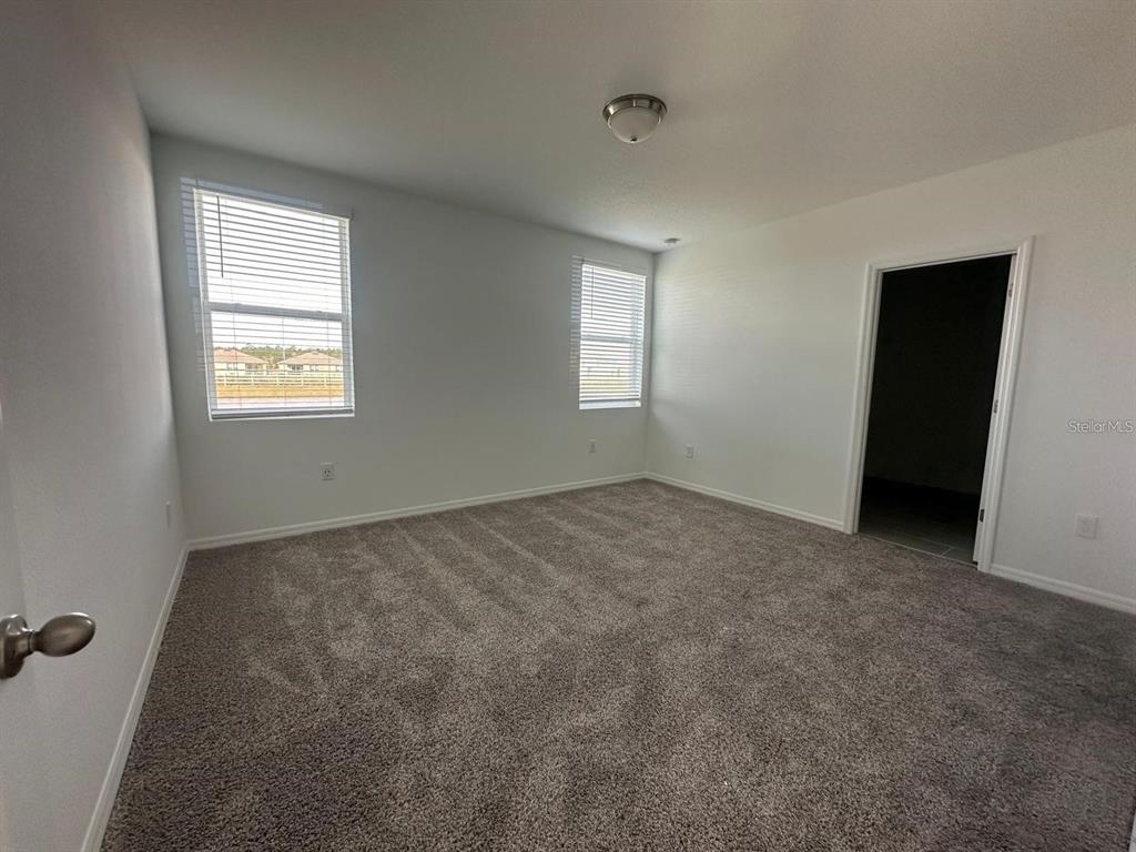 An empty bedroom features gray carpet, white walls, two windows, and a doorway — 2748 SAN MARCO WAY, WINTER HAVEN, FL