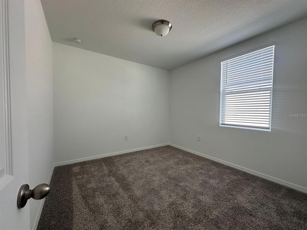 An empty bedroom features white walls, gray carpet, a ceiling light, and a window with blinds — 2748 SAN MARCO WAY, WINTER HAVEN, FL
