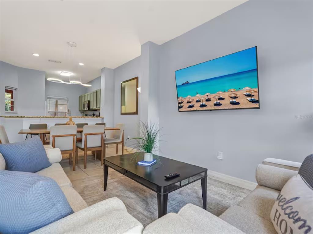 A living room features a wall-mounted television, a coffee table, and an adjacent dining area — 3113 YELLOW LANTANA LANE, KISSIMMEE, FL