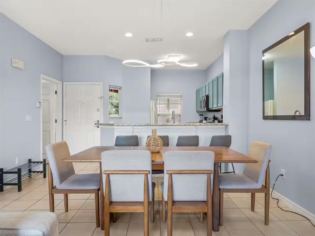 A dining area features a wooden table with six chairs, a modern light fixture, and kitchen — 3113 YELLOW LANTANA LANE, KISSIMMEE, FL