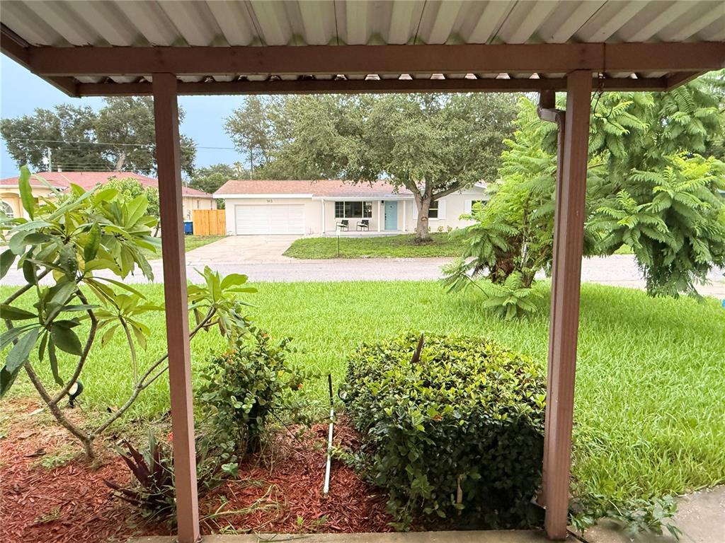 A view from a covered porch looking across a lawn toward a single-story house — 164 PINEWOOD AVENUE, CLEARWATER, FL