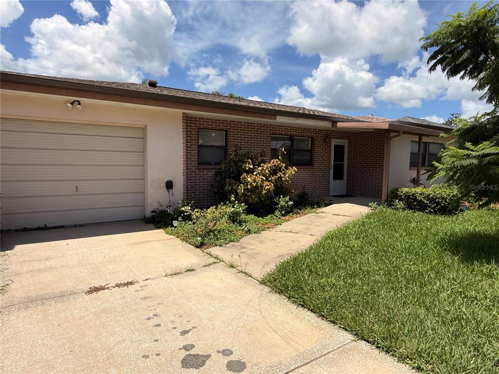A single-story brick house features a garage, a concrete driveway, and a front walkway — 164 PINEWOOD AVENUE, CLEARWATER, FL