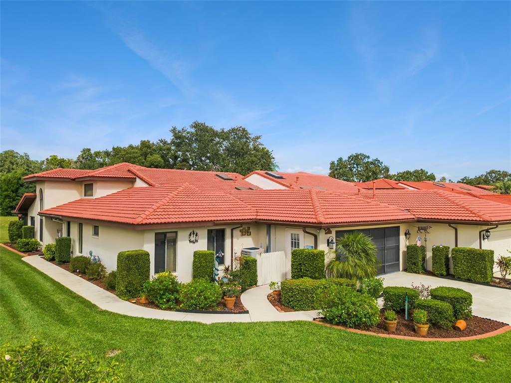 A single-story house with a red tile roof, white stucco walls, and manicured landscaping — 2697 CLUBHOUSE DRIVE, LAKE WALES, FL