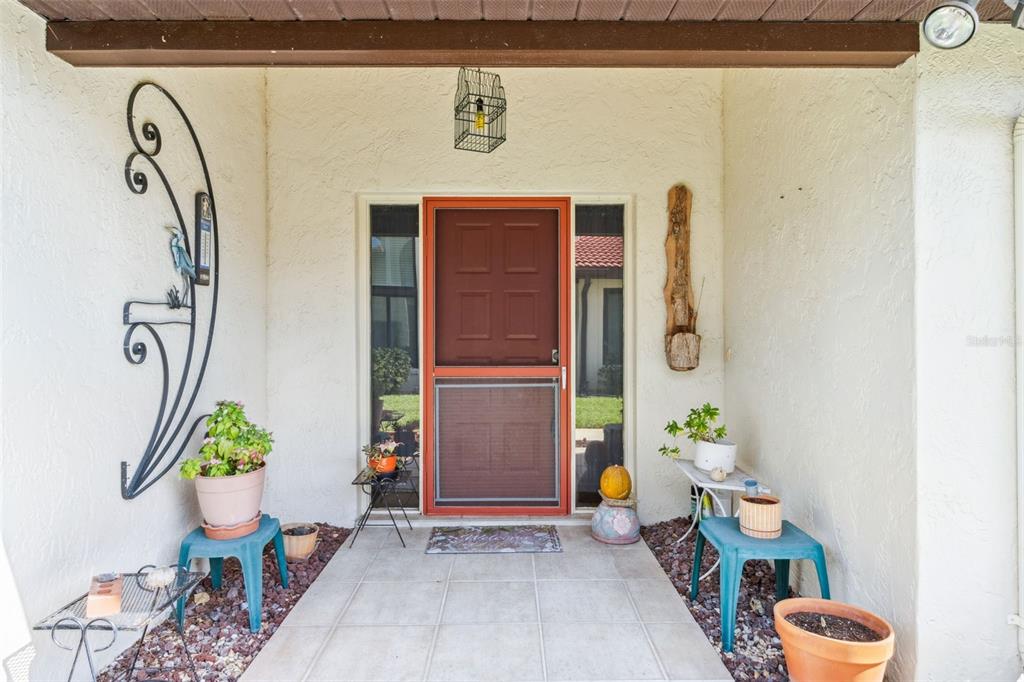 A front entryway features a red screen door, tiled flooring, and potted plants on stools — 2697 CLUBHOUSE DRIVE, LAKE WALES, FL