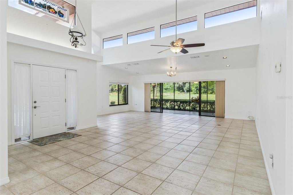 A spacious, tiled living area features high ceilings, clerestory windows, and sliding glass patio doors — 2697 CLUBHOUSE DRIVE, LAKE WALES, FL