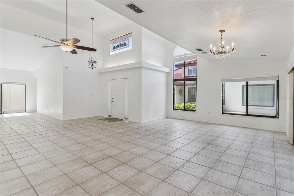 A spacious living area features white walls, tiled floors, high ceilings, and large windows — 2697 CLUBHOUSE DRIVE, LAKE WALES, FL