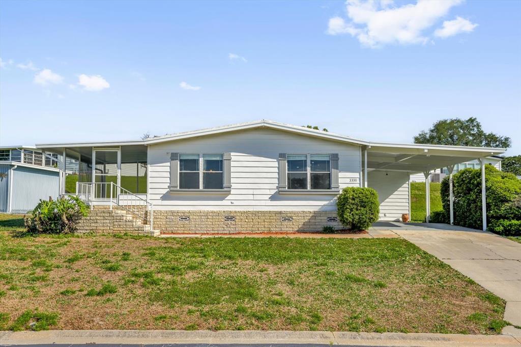 A single-story manufactured home with white siding, a brick base, and an attached carport — 3338 N CITRUS CIRCLE UNIT 1679, ZELLWOOD, FL
