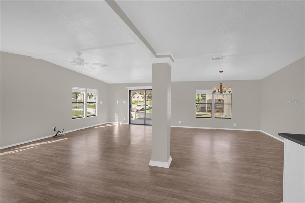An open-concept living and dining area features light wood-look flooring and a central support pillar — 3338 N CITRUS CIRCLE UNIT 1679, ZELLWOOD, FL