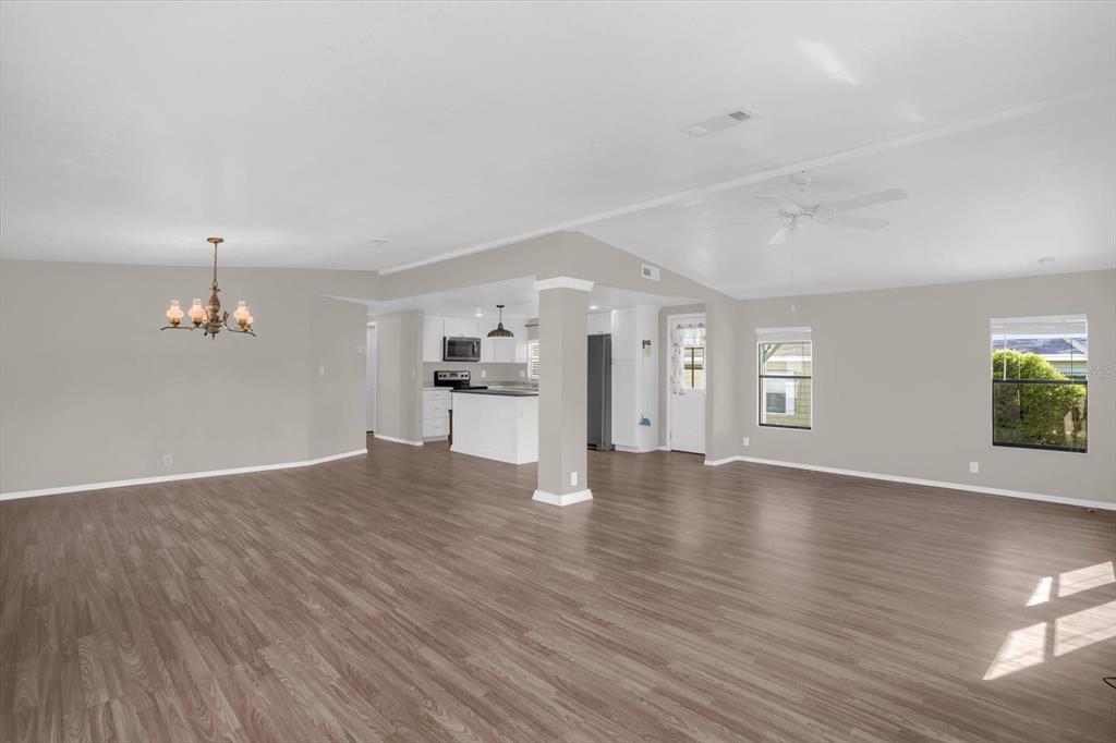 An open-concept living area features wood-look flooring, a central support column, and a kitchen beyond — 3338 N CITRUS CIRCLE UNIT 1679, ZELLWOOD, FL
