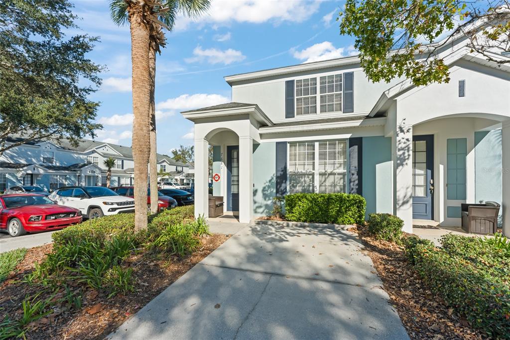 A two-story light blue townhouse with a concrete driveway and a small front garden — 7681 SIR KAUFMANN COURT, KISSIMMEE, FL