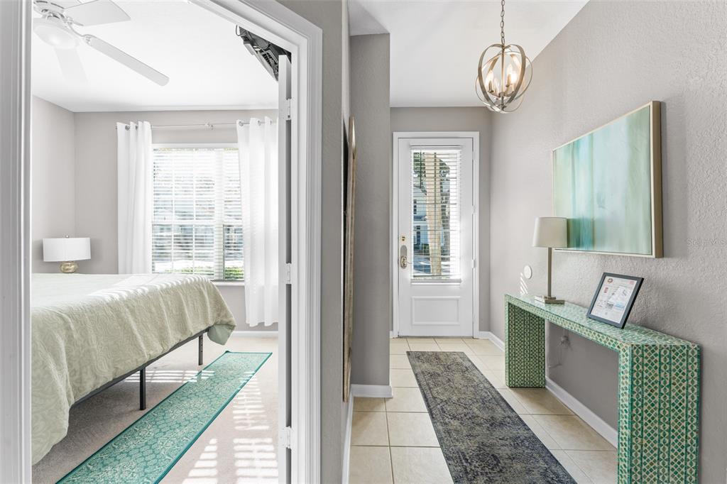 A view from a doorway into a bedroom and a tiled entryway with a console table — 7681 SIR KAUFMANN COURT, KISSIMMEE, FL