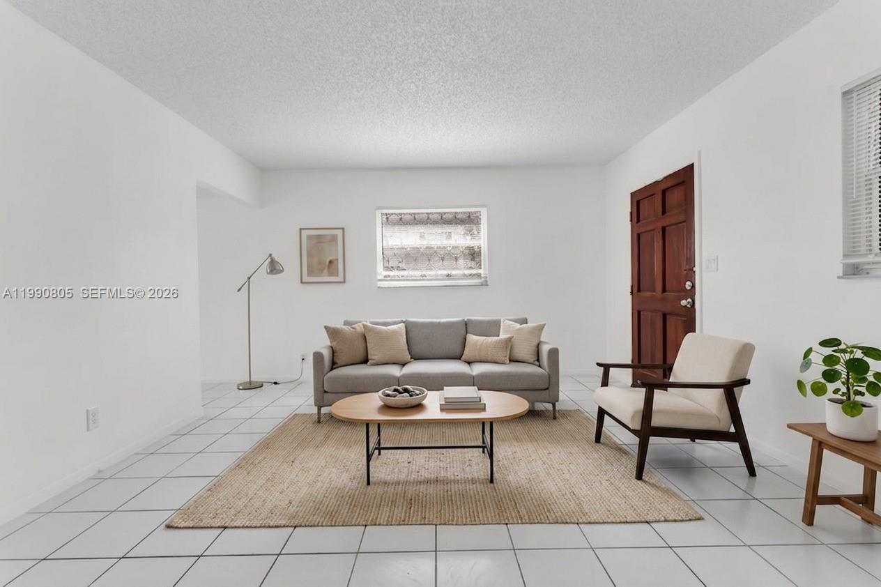 A living room features white tile floors, a grey sofa, and a wooden front door — 321 SW 1st Ct # 4, Pompano Beach FL 33060, POMPANO BEACH, FL