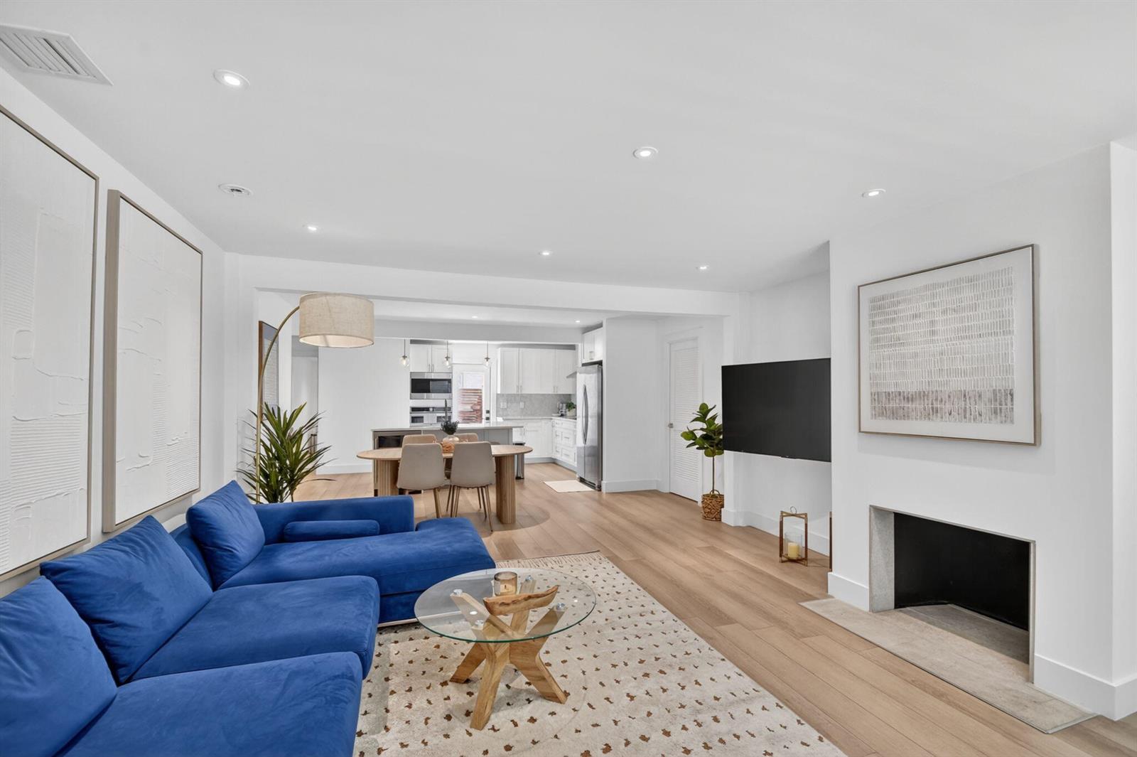 A bright open-concept living room features a blue sectional sofa, fireplace, and adjacent dining area — 4811 N Flagler Drive, West Palm Beach FL 33407, WEST PALM BEACH, FL