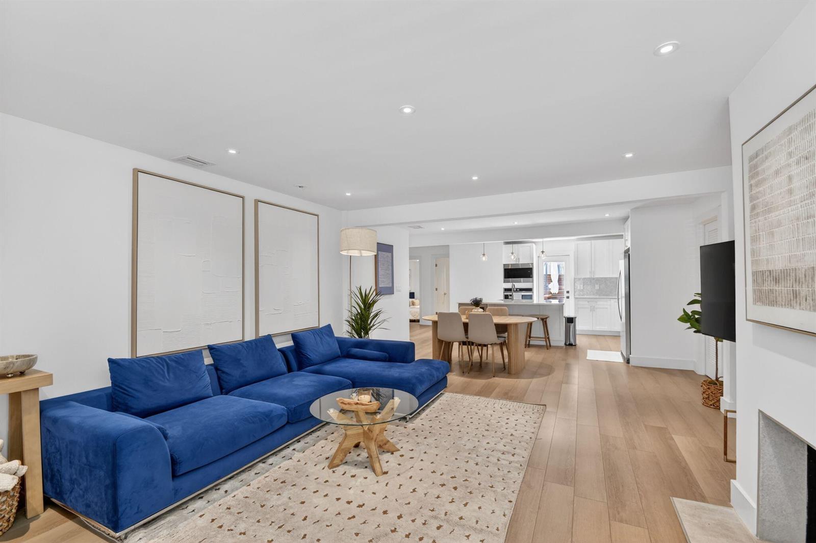 A bright living room features a blue sectional sofa, a glass coffee table, and hardwood floors — 4811 N Flagler Drive, West Palm Beach FL 33407, WEST PALM BEACH, FL