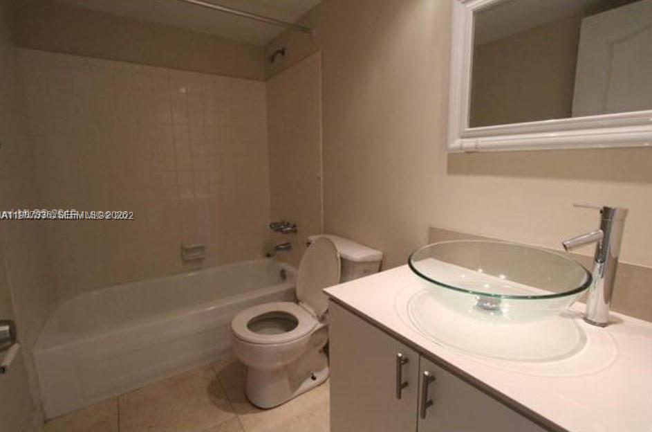 A bathroom features a glass vessel sink, a white vanity, a toilet, and a bathtub — 5775 W 20th Ave # 406, Hialeah FL 33012, HIALEAH, FL