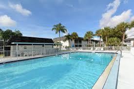 A rectangular swimming pool sits in front of a multi-story apartment building with palm trees — 4509 3RD STREET CIRCLE W UNIT 283, BRADENTON, FL