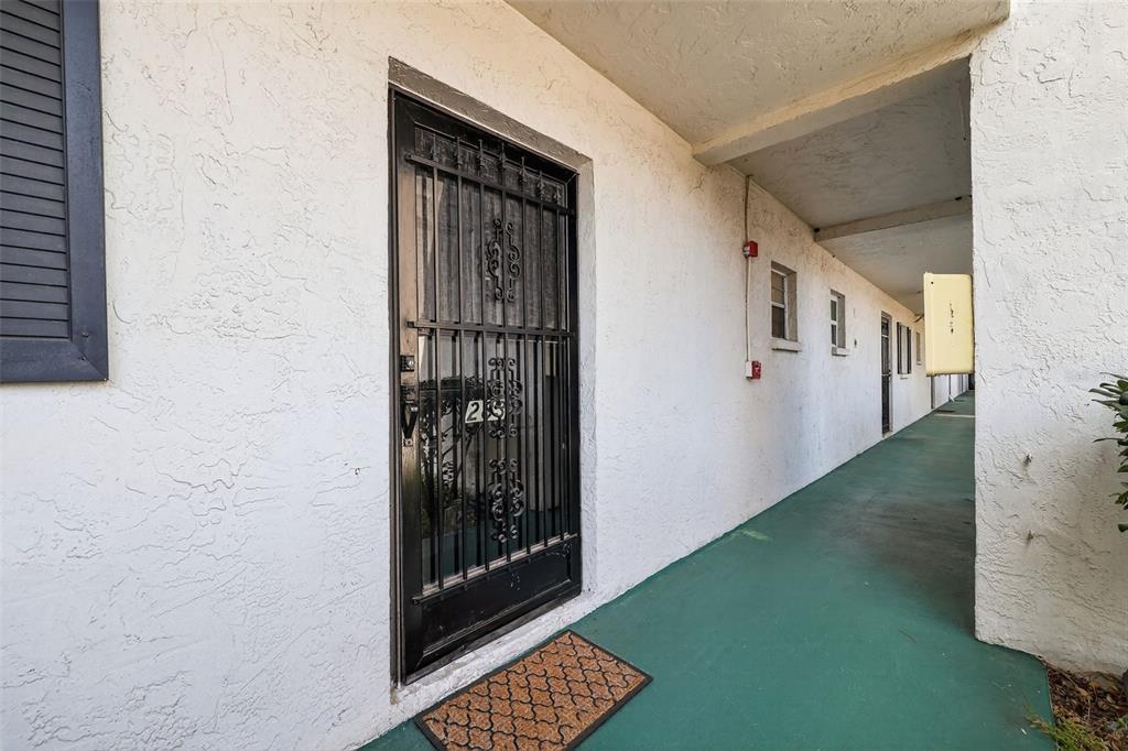 An exterior view of a building corridor with a black security door and green flooring — 4509 3RD STREET CIRCLE W UNIT 283, BRADENTON, FL
