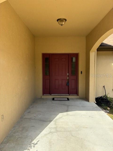 A covered concrete entryway leads to a red front door with sidelights — 20929 SW AUDUBON AVENUE, DUNNELLON, FL