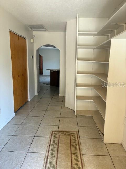 A tiled hallway features a wooden closet door, an arched entryway, and built-in white shelving — 20929 SW AUDUBON AVENUE, DUNNELLON, FL
