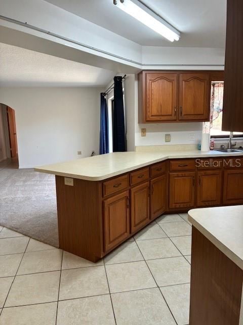 A kitchen features wood cabinets, a light-colored countertop, and tile flooring, opening into a living area — 20929 SW AUDUBON AVENUE, DUNNELLON, FL