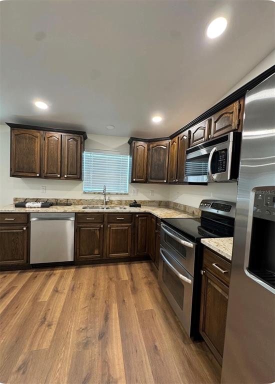 A kitchen features dark wood cabinets, stainless steel appliances, and wood-look flooring — 14 MILL STREET, TARPON SPRINGS, FL