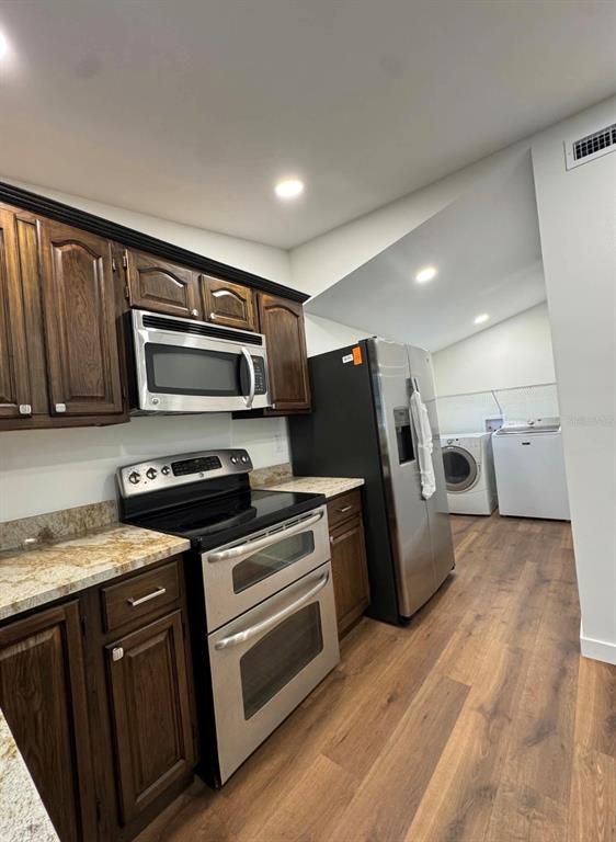 A kitchen features dark wood cabinets, stainless steel appliances, granite countertops, and wood-look flooring — 14 MILL STREET, TARPON SPRINGS, FL