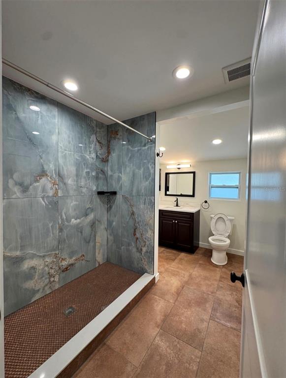 A bathroom features a large walk-in shower with blue marble-look tiles and brown floor tiles — 14 MILL STREET, TARPON SPRINGS, FL
