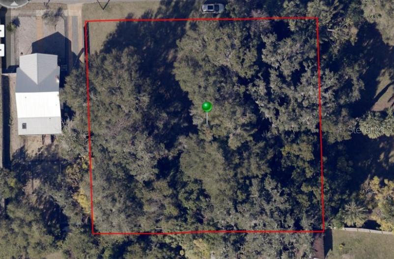 An aerial view shows a rectangular, tree-covered vacant lot outlined in red — W MAY STREET, DELAND, FL