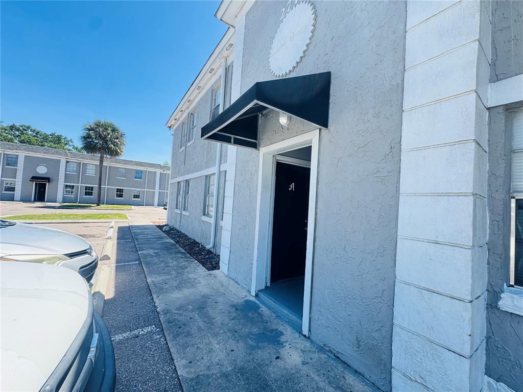 An exterior view of a gray apartment building entrance with a black awning and door — 2777 L B MCLEOD ROAD UNIT 2777A, ORLANDO, FL