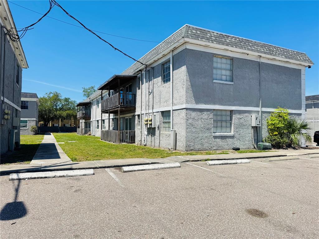 A two-story apartment building with gray stucco walls and wooden balconies sits beside a parking lot — 2777 L B MCLEOD ROAD UNIT 2777A, ORLANDO, FL