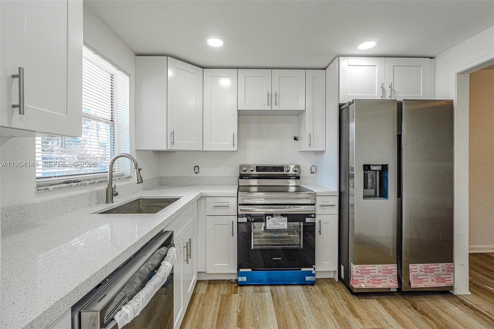 A modern kitchen features white cabinets, stainless steel appliances, and light-colored quartz countertops — 5100 SW 64th Ave # 106, Davie FL 33314, DAVIE, FL