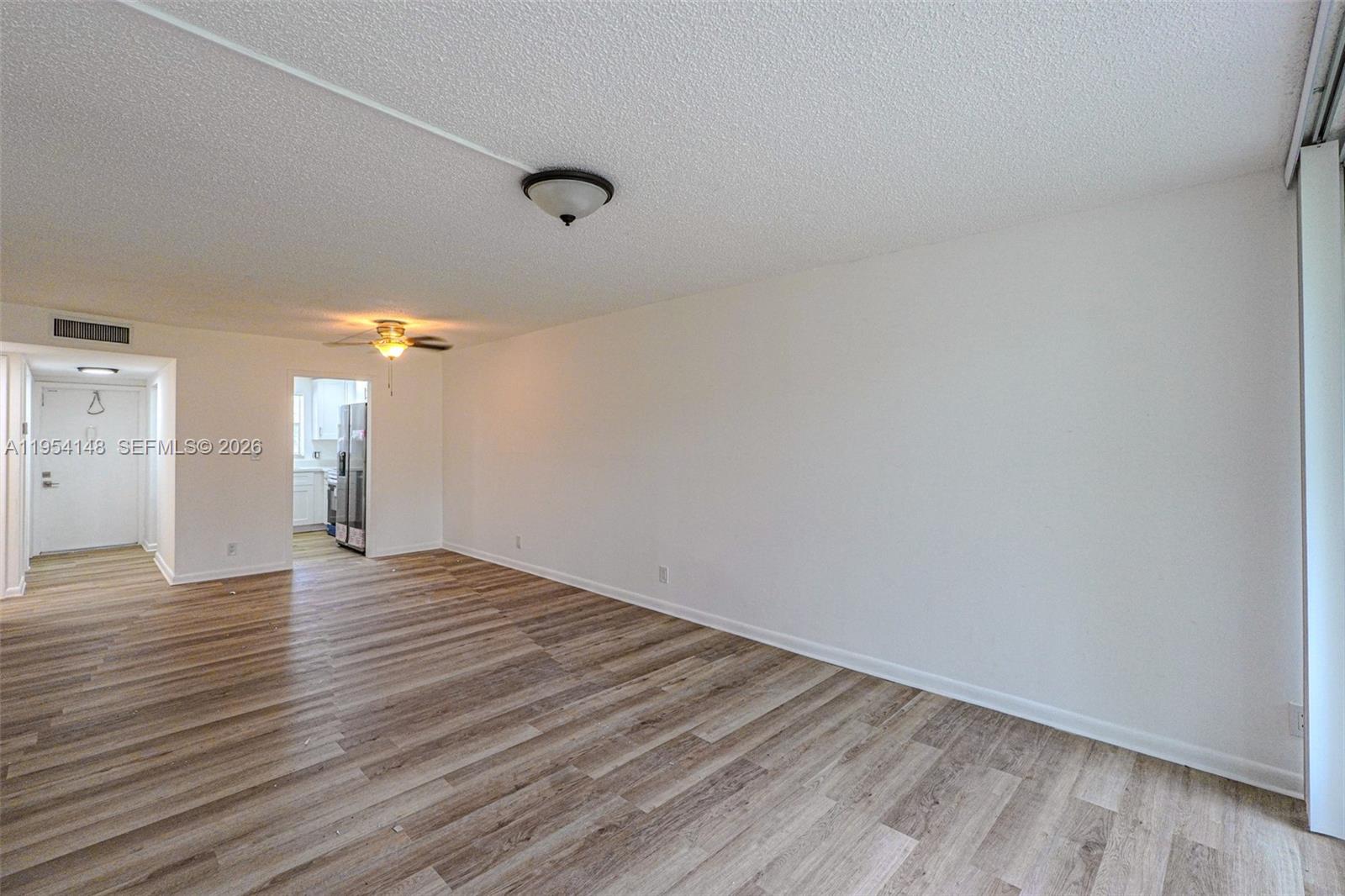 An empty living room features wood-look flooring, white walls, and a ceiling fan — 5100 SW 64th Ave # 106, Davie FL 33314, DAVIE, FL