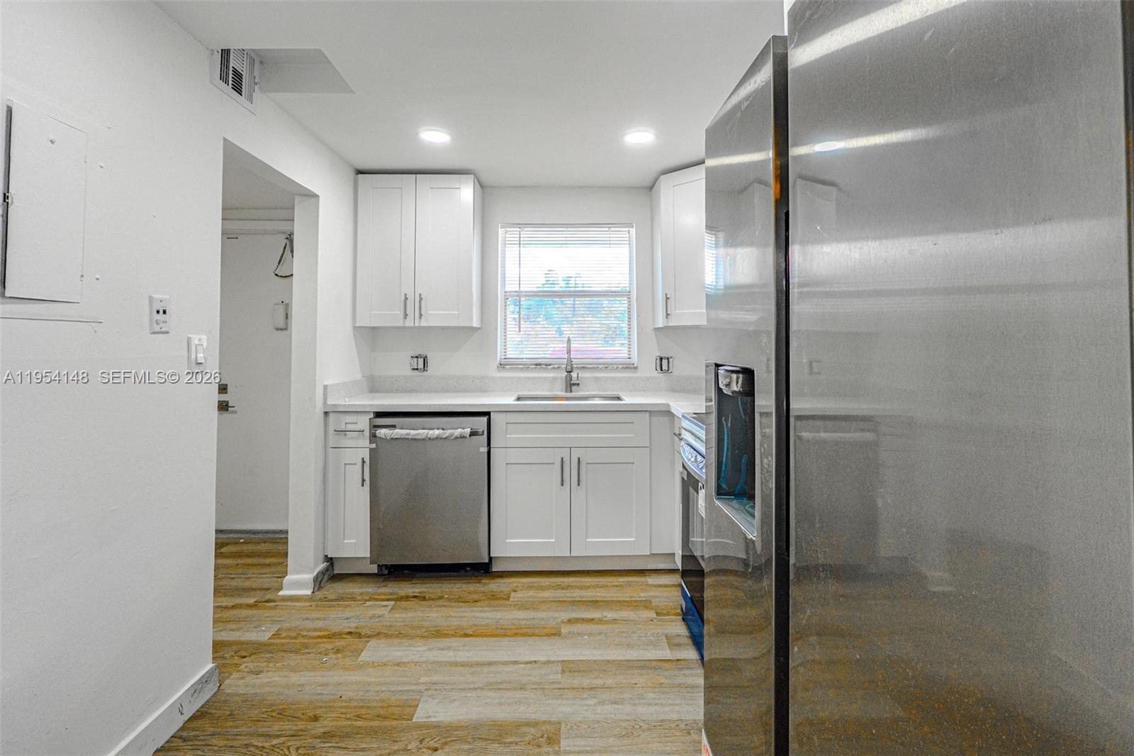 A kitchen features white cabinets, stainless steel appliances, and wood-look flooring — 5100 SW 64th Ave # 106, Davie FL 33314, DAVIE, FL