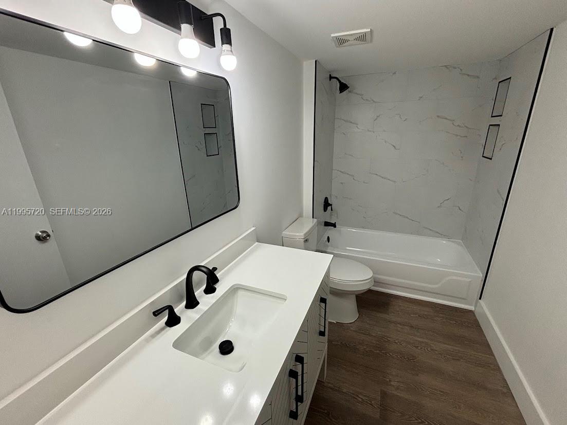 A modern bathroom features a white vanity, a large mirror, and a tiled tub shower — 460 S Park Rd # 110, Hollywood FL 33021, HOLLYWOOD, FL